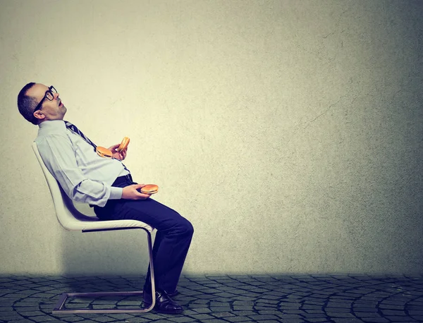 Uomo d'affari sensazione di stanchezza e sonno dopo aver mangiato troppi hamburger per il pranzo — Foto Stock