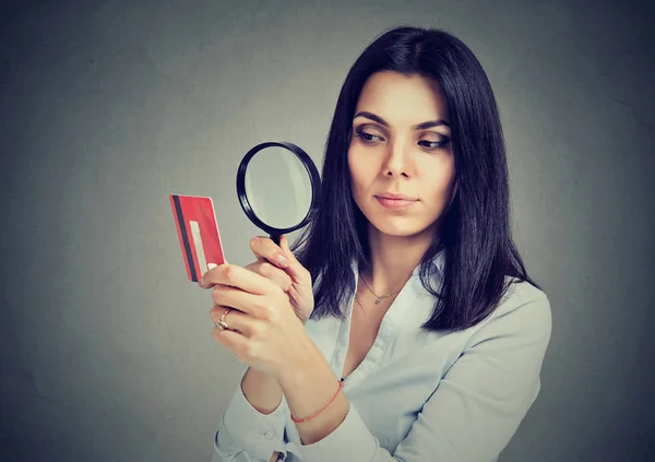 Curiosa donna d'affari guardando la carta di credito attraverso lente di ingrandimento — Foto Stock