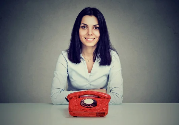 Mujer feliz sentada en la mesa con teléfono rojo vintage —  Fotos de Stock