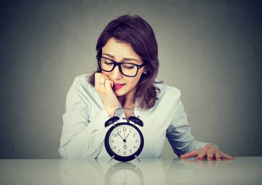 Endişeli işkadını endişeyle alarm saat bakarak 