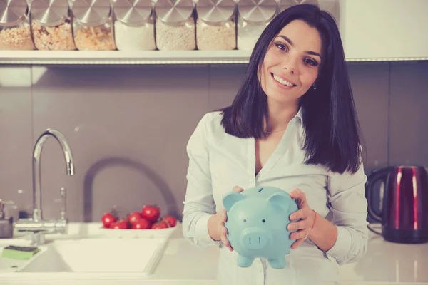 Gelukkige vrouw met piggy bank in haar nieuwe appartement huis — Stockfoto