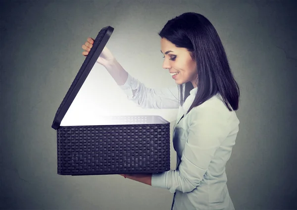 Mujer que se abre mirando en la caja de regalo con luz brillante saliendo —  Fotos de Stock