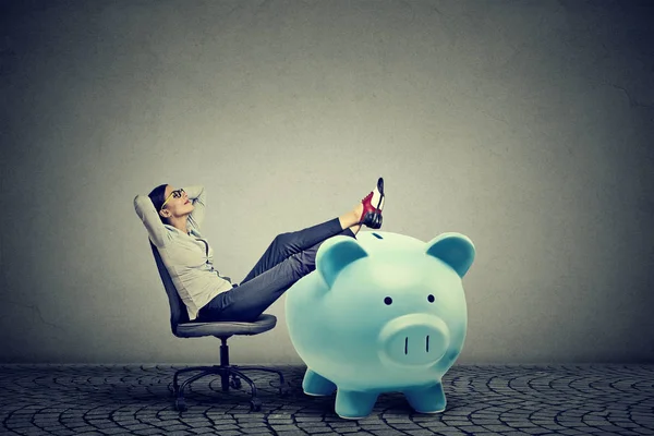 Businesswoman with big piggy bank relaxing sitting on chair — Stock Photo, Image