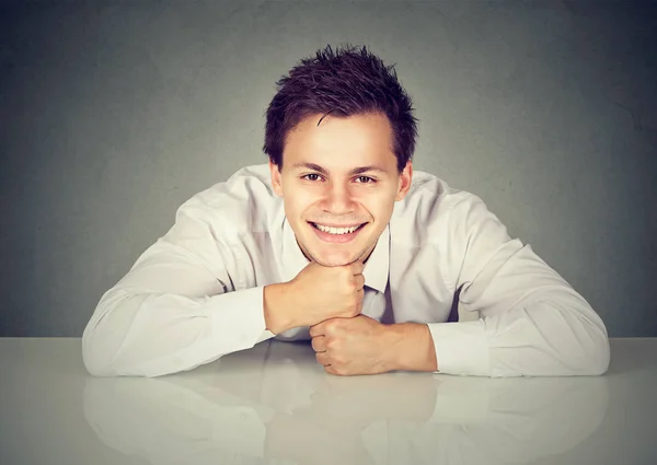 Jóképű férfi fehér asztalnál hajol, és mosolyogva kamera — Stock Fotó