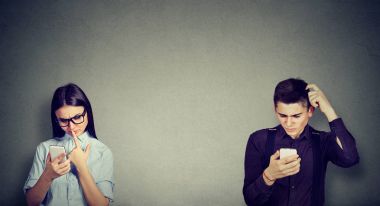 Perplexed man and woman looking at mobile phone  clipart