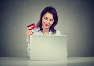 Kredi kartı ile alışveriş dizüstü bilgisayar kullanarak çevrimiçi gülümseyen kadın 