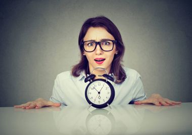 Endişeli kadın üzerinden küçük toplama tablo alarmlı saat. 