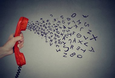 Alfabe harfleri gelme dışarı ile telefon cep telefonu tutan el. Çok fazla kelime 