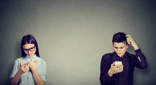 Озадаченные мужчина и женщина смотрят на мобильный телефон — стоковое фото