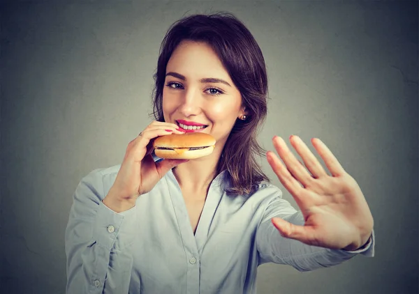 Feliz joven mujer dice no a las restricciones de dieta disfrutando de su hamburguesa con queso —  Fotos de Stock