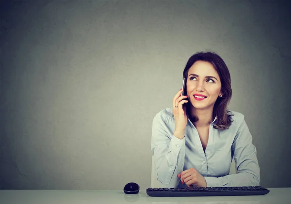 Молодая деловая женщина, сидящая за столом офиса и разговаривающая по мобильному телефону — стоковое фото