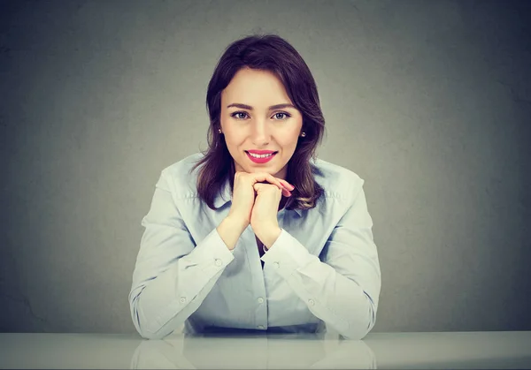 Mujer feliz inclinada a la mesa sonriendo a la cámara — Foto de Stock