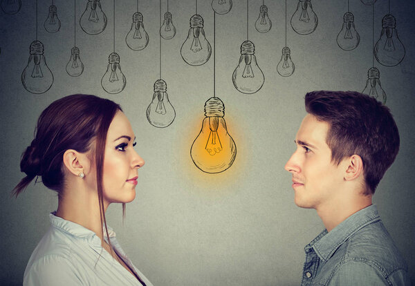 Cognitive skills ability concept, male vs female. Man and woman looking at bright light bulb 