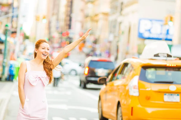 一个年轻的女人，海陵一辆黄色出租车在纽约城的街道上散步的时候 — 图库照片