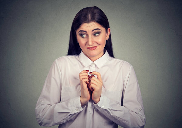 Portrait of a woman in awkward situation, playing nervously with hands. 
