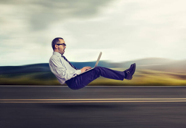 Fast internet concept. Levitating business man on road using laptop compute