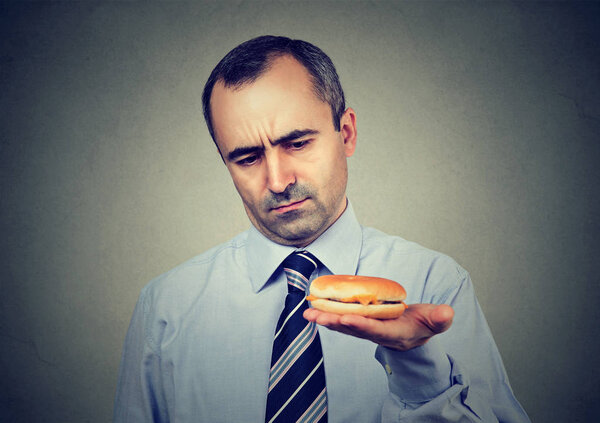 Serious mature man looking at cheeseburger 