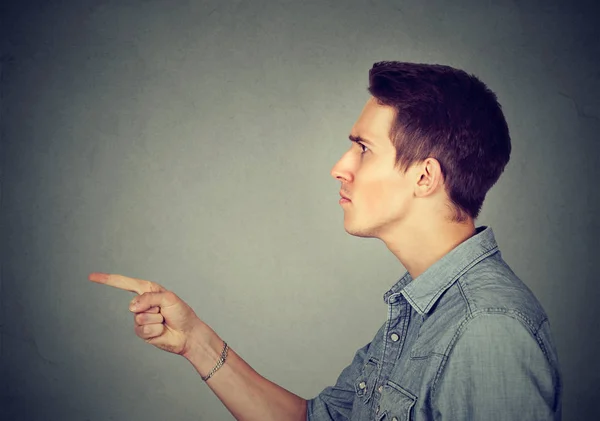Angry young man pointing finger at someone — Stock Photo, Image
