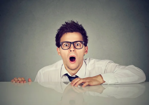 Shocked scared young man coming out from under the table — Stock Photo, Image