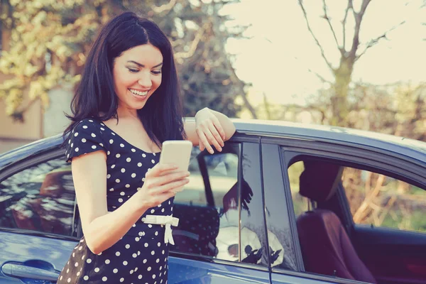 Framgångsrik ung kvinna som står vid hennes bil SMS på mobiltelefon — Stockfoto