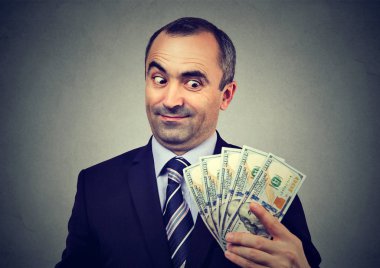 Funny sly business man holding looking at money dollar banknotes  clipart