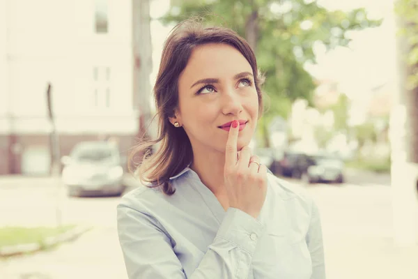 Happy woman thinking and looking sideways standing on a city street — Stock Photo, Image