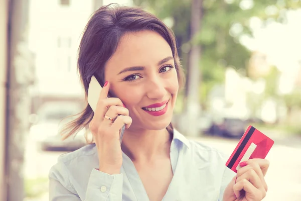 Счастливая женщина покупает онлайн, делая покупки со смартфоном на улице — стоковое фото