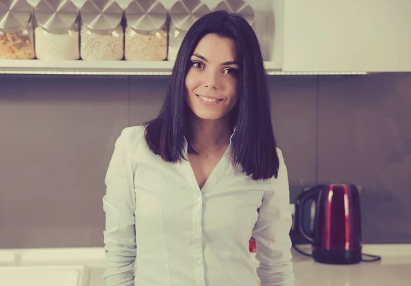 Business woman in casual clothes looking at camera and smiling while standing in a kitchen — Stock Photo, Image