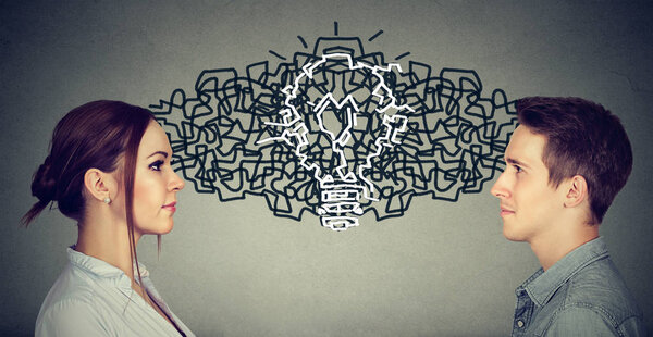 Man and woman looking at each other exchanging their thoughts coming up together with an idea light bulb 