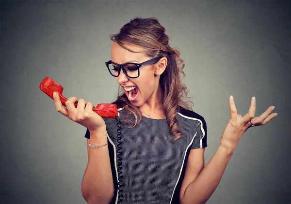 Young angry woman yelling into red phone — Stock Photo, Image