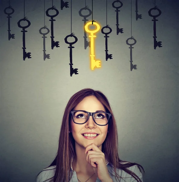 Donna sorridente guardando la chiave d'oro vintage per il successo tra molti altri appeso . — Foto Stock