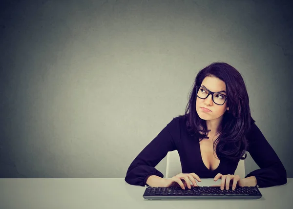 Ernsthafte besorgte junge Frau sitzt am Schreibtisch und tippt auf der Tastatur eines Desktops — Stockfoto