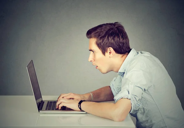 Chockad förbryllad man sitter framför bärbar dator tittar på skärmen — Stockfoto