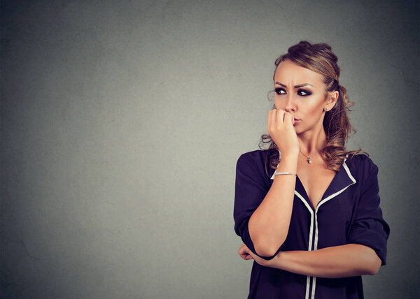 Занятая беспокойная женщина грызет ногти, глядя в сторону
 