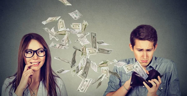 Sad man looking at his wallet with money dollar banknotes flying away towards flirting cute young woman — Stock Photo, Image