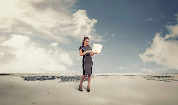 Young business woman in a desert using a laptop computer — Stock Photo, Image