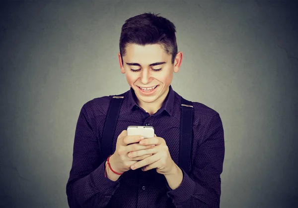 Młody człowiek szczęśliwy, przy użyciu telefonu komórkowego uśmiechnięty — Zdjęcie stockowe