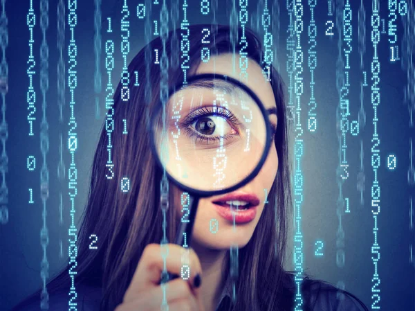 Vigilancia del concepto de ciberdelincuencia. Mujer curiosa mirando a través de una lupa y el fondo de código binario de la computadora —  Fotos de Stock