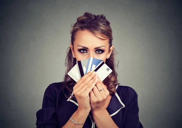Femme sérieuse cachant visage derrière de nombreuses cartes de crédit — Photo