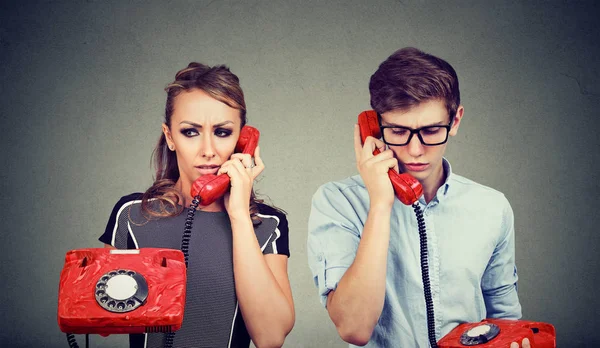 Triste confuso jovem casal homem e mulher conversando uns com os outros pelo telefone — Fotografia de Stock