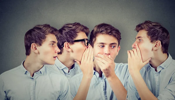 Tres jóvenes susurrándose unos a otros y sorprendiendo al tipo asombrado en el oído . — Foto de Stock