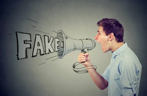 Side profile of a young man screaming in a megaphone spreading fake news — Stock Photo, Image