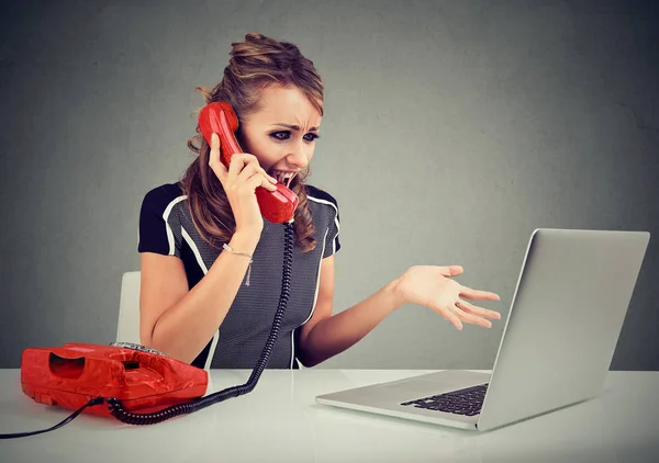 Angry young woman calling customer service with a laptop failure — Stock Photo, Image