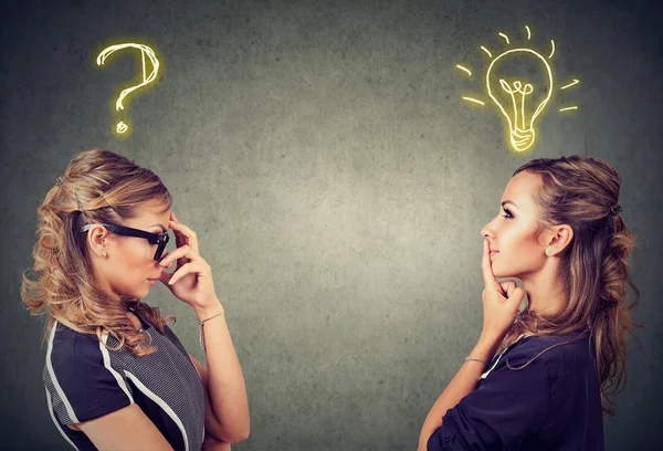 Two women thinking one has a question another solution with light bulb above head — Stock Photo, Image