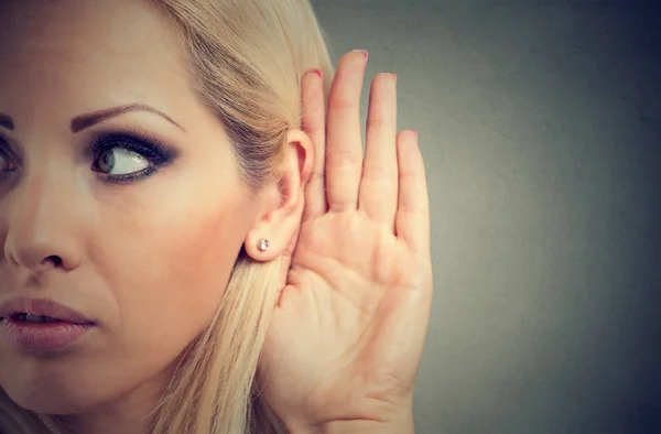 Vrouw houdt haar hand in de buurt van oor en luistert aandachtig — Stockfoto