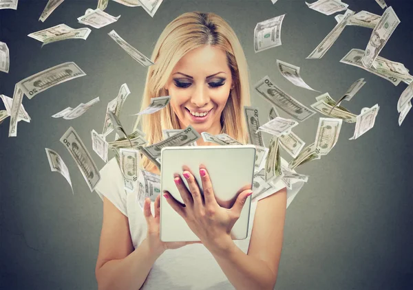 Online banking money transfer concept. Happy woman using tablet computer with dollar bills flying away from screen — Stock Photo, Image