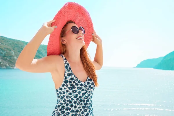 Europa Grécia viagens de férias. Mulher desfrutando do tempo ensolarado à beira-mar. Jovem senhora vivendo estilo de vida fantasia vestindo chapéu vermelho nas férias . — Fotografia de Stock