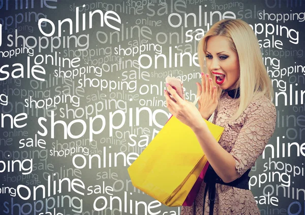 Excited woman shopping online checking prices on mobile phone. Surprised girl with colorful bags looking at cellphone — Stock Photo, Image