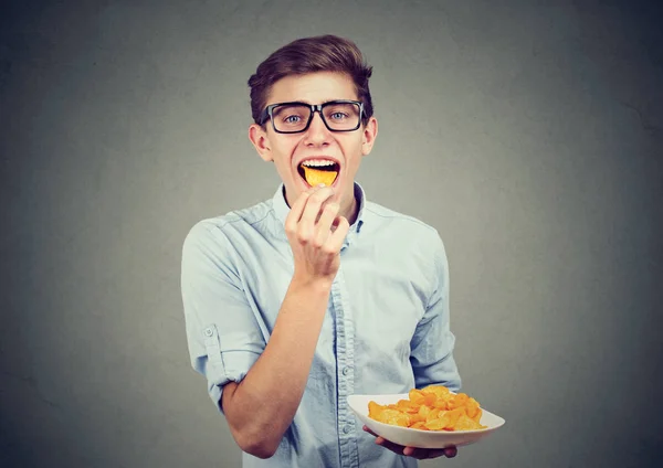 Jeune homme à lunettes manger des croustilles — Photo