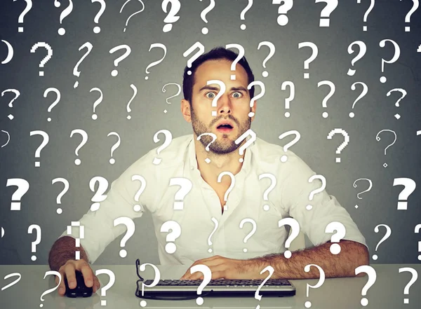 Perplexed man working on desktop computer has many questions — Stock Photo, Image